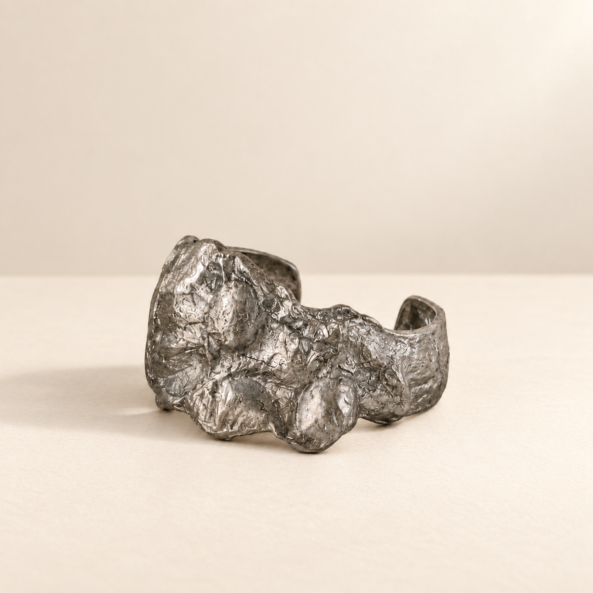 Silver Fault — Sculptural Paper Cuff Bracelet resting on a warm ivory studio surface with a natural grounding shadow — Niksa Design