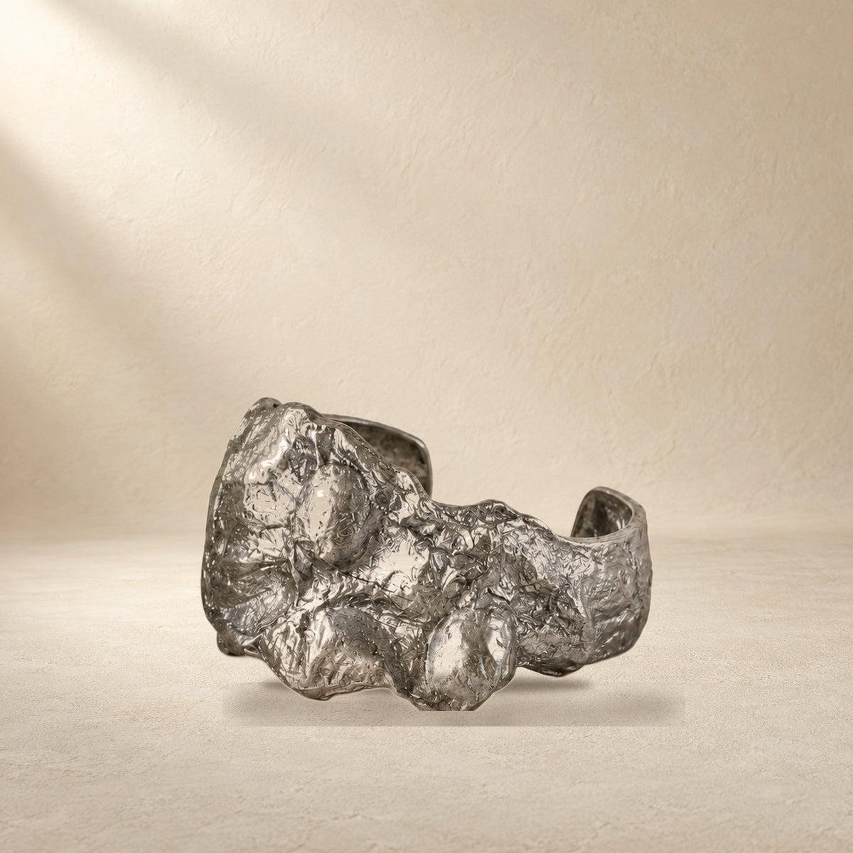 Silver Fault bracelet resting on a warm cream surface