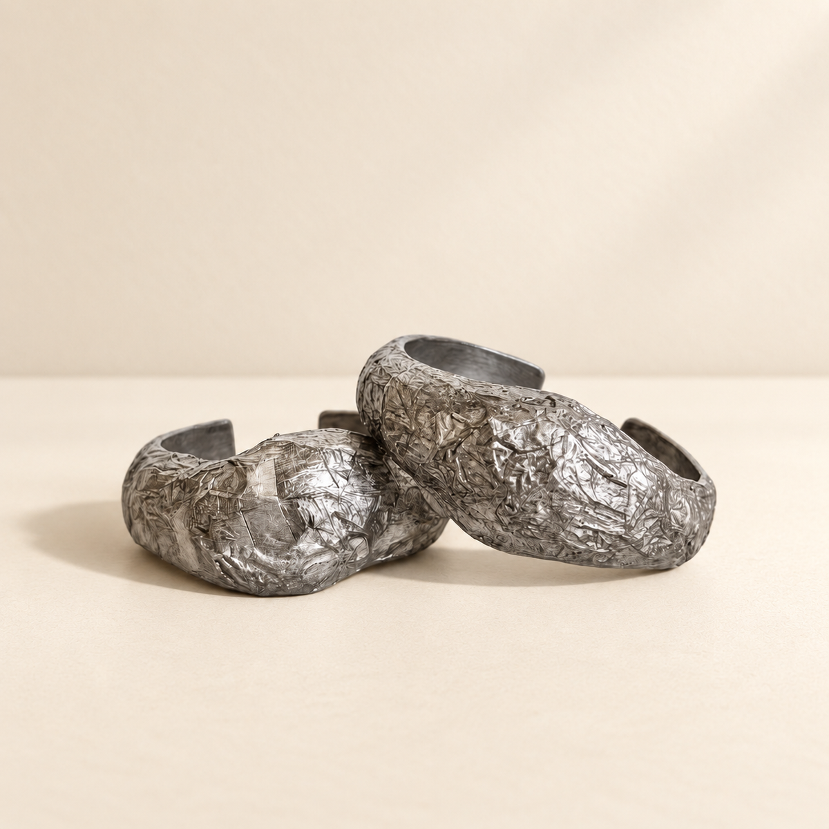 Silver Strata — Sculptural Paper Cuff Bracelet resting on a warm ivory studio surface with a natural grounding shadow — Niksa Design