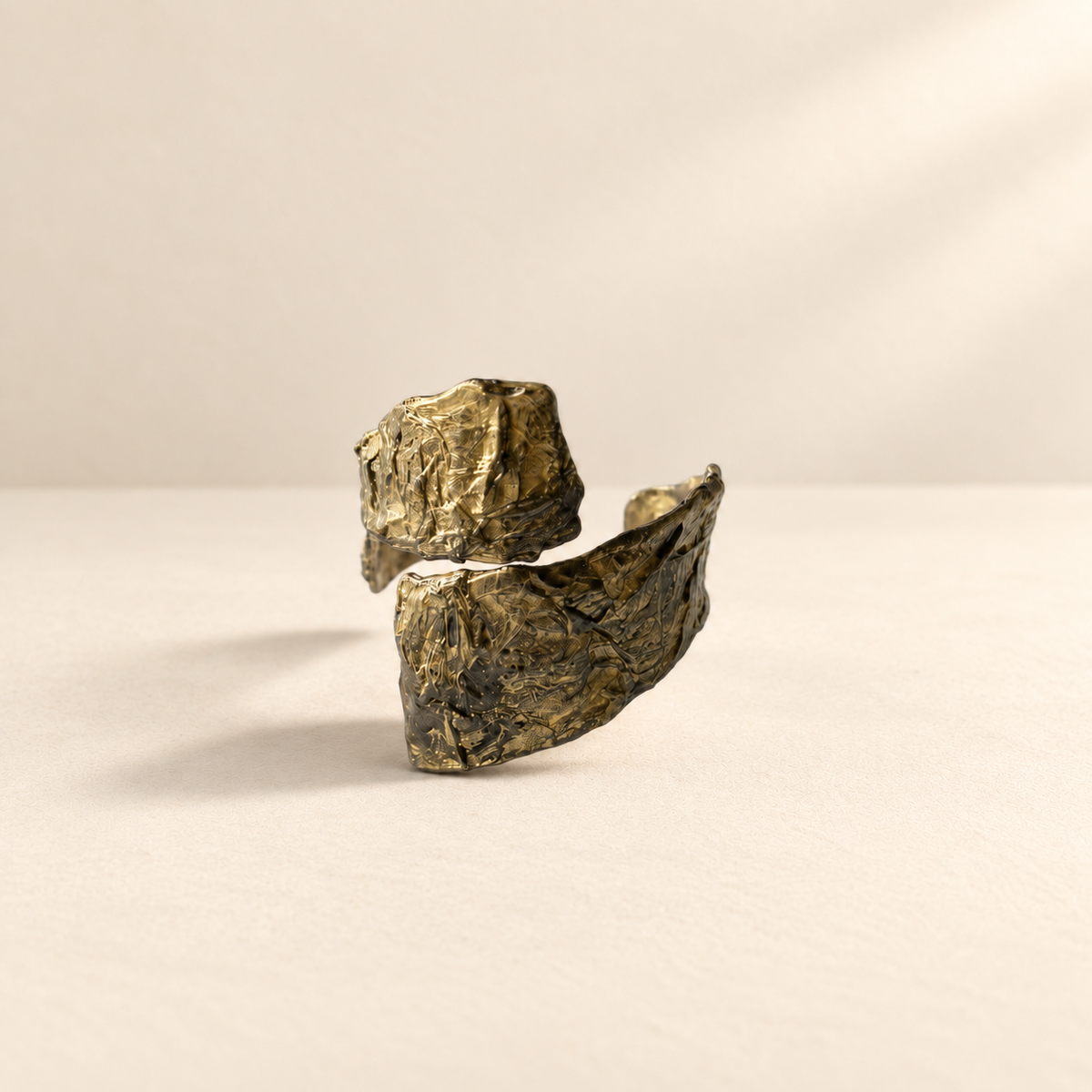 Divided Current — Sculptural Paper Cuff Bracelet resting on a warm ivory studio surface with a natural grounding shadow — Niksa Design