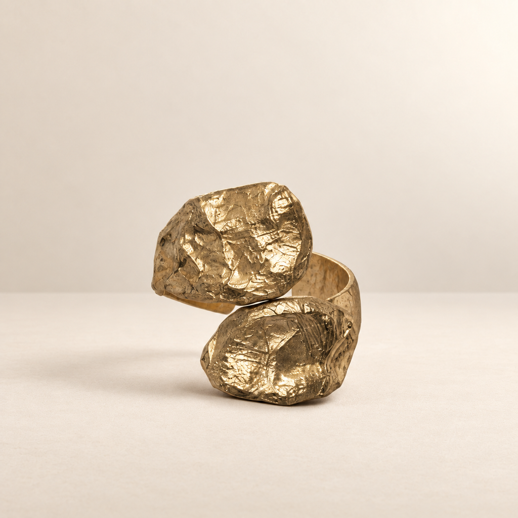 Twin Tension sculptural paper cuff bracelet in a gold-toned finish on a warm ivory surface — Niksa Design