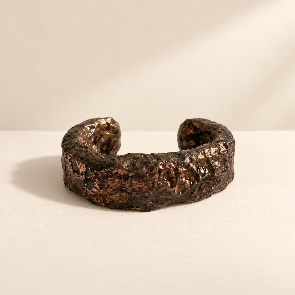 Bronze Horizon — Sculptural Paper Cuff Bracelet resting on a warm ivory studio surface with a natural grounding shadow — Niksa Design
