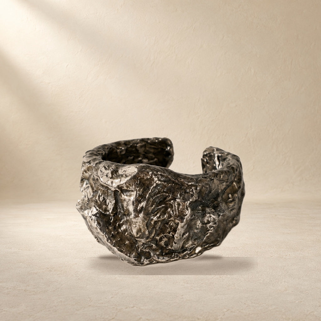 Compressed Shield bracelet resting on a warm cream surface
