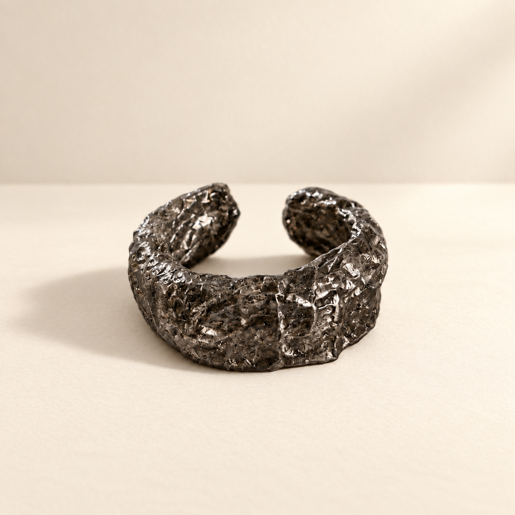 Folded Strata — Sculptural Paper Cuff Bracelet resting on a warm ivory studio surface with a natural grounding shadow — Niksa Design