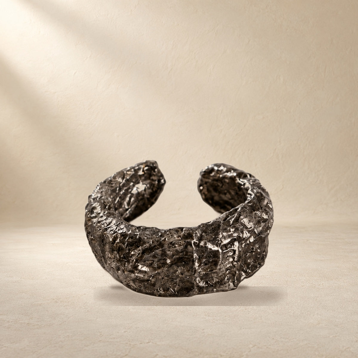 Folded Strata bracelet resting on a warm cream surface
