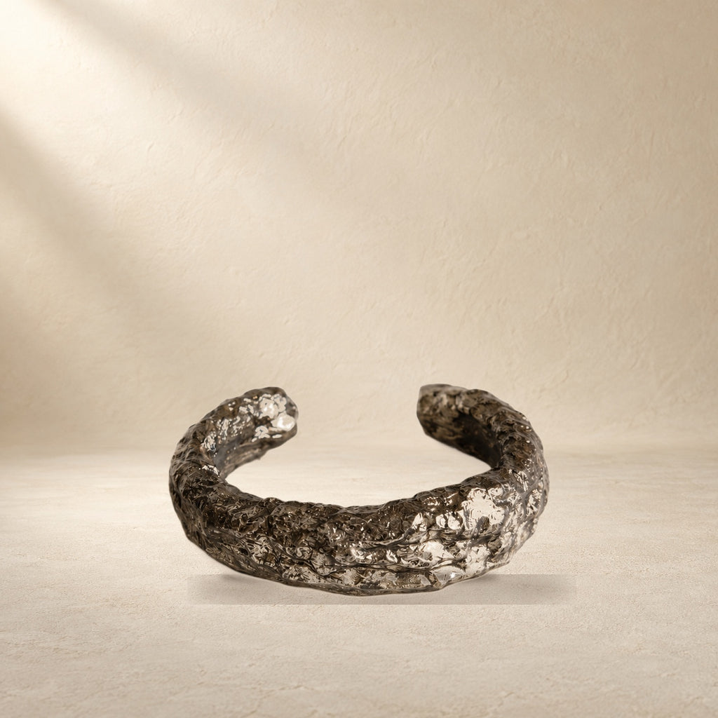 Silver Arc bracelet resting on a warm cream surface