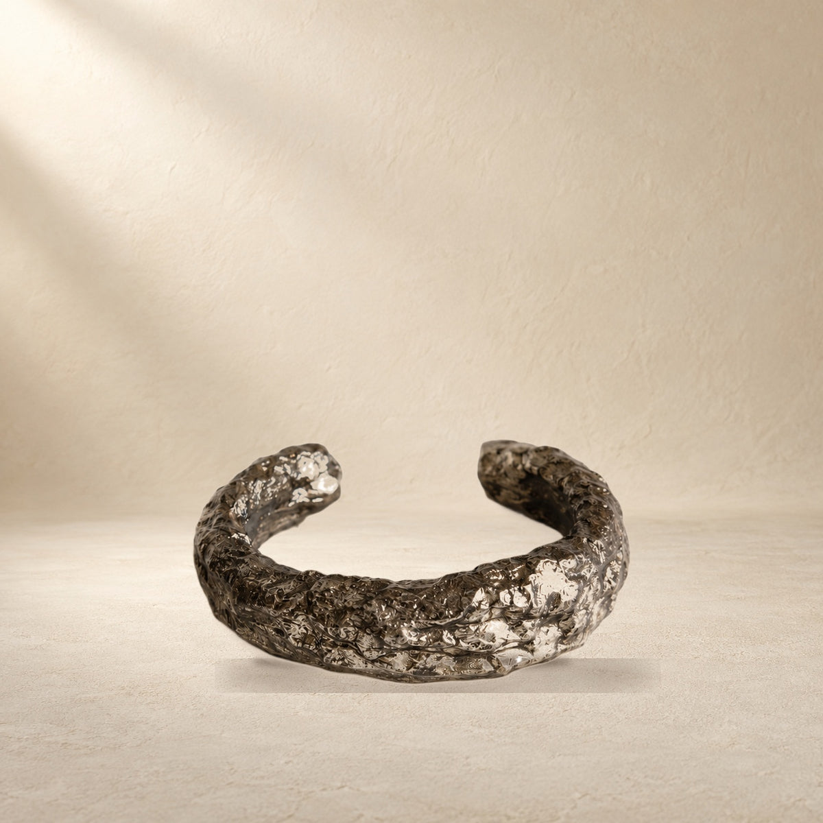 Silver Arc bracelet resting on a warm cream surface