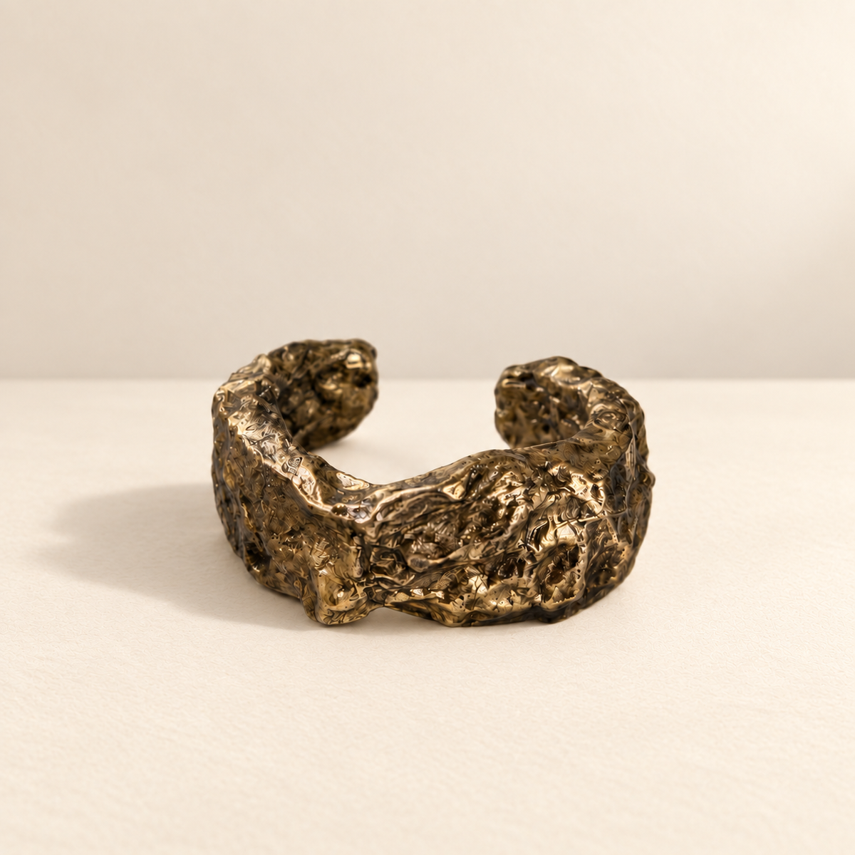Gilded Swell — Sculptural Paper Cuff Bracelet resting on a warm ivory studio surface with a natural grounding shadow — Niksa Design