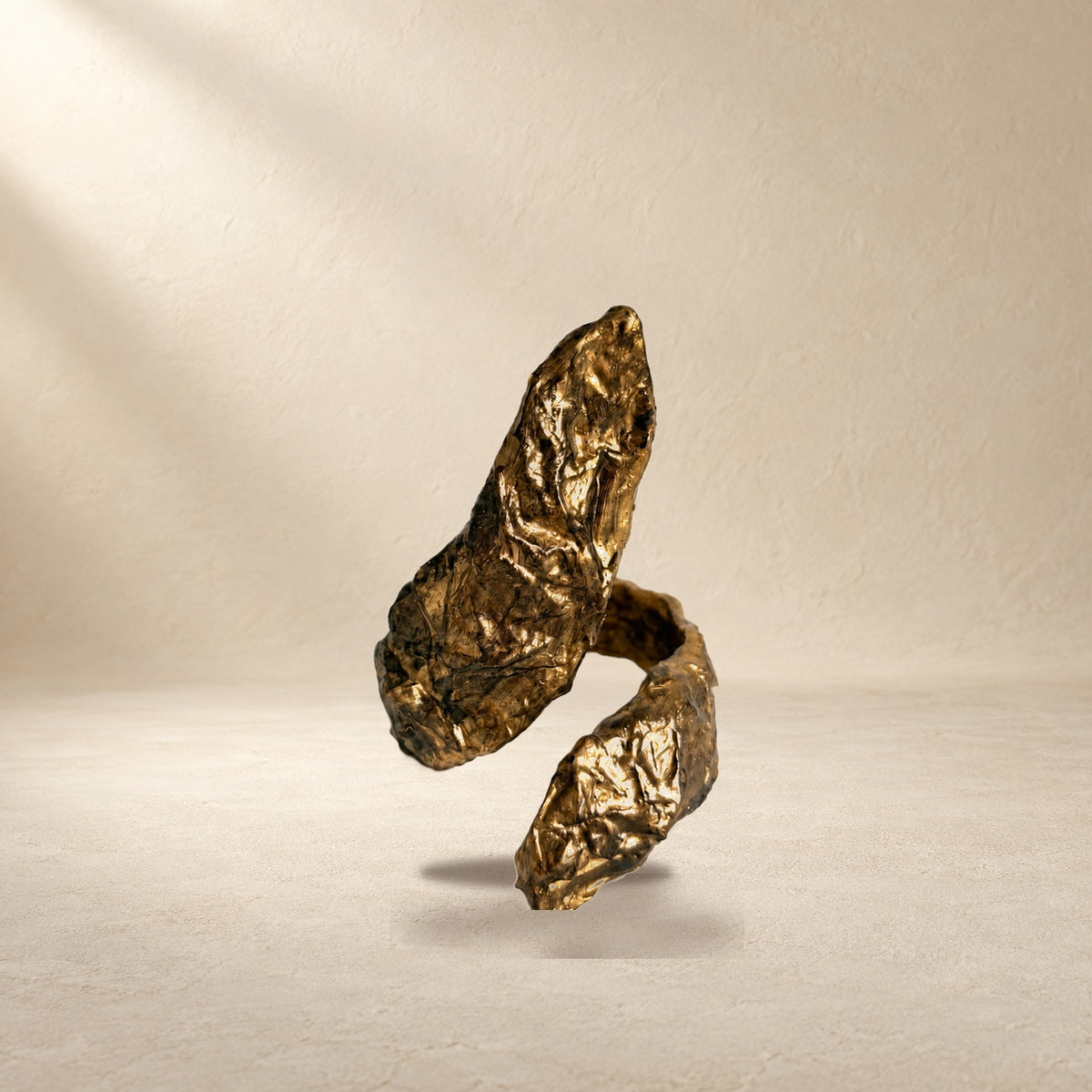 Gilded Reach bracelet resting on a warm cream surface
