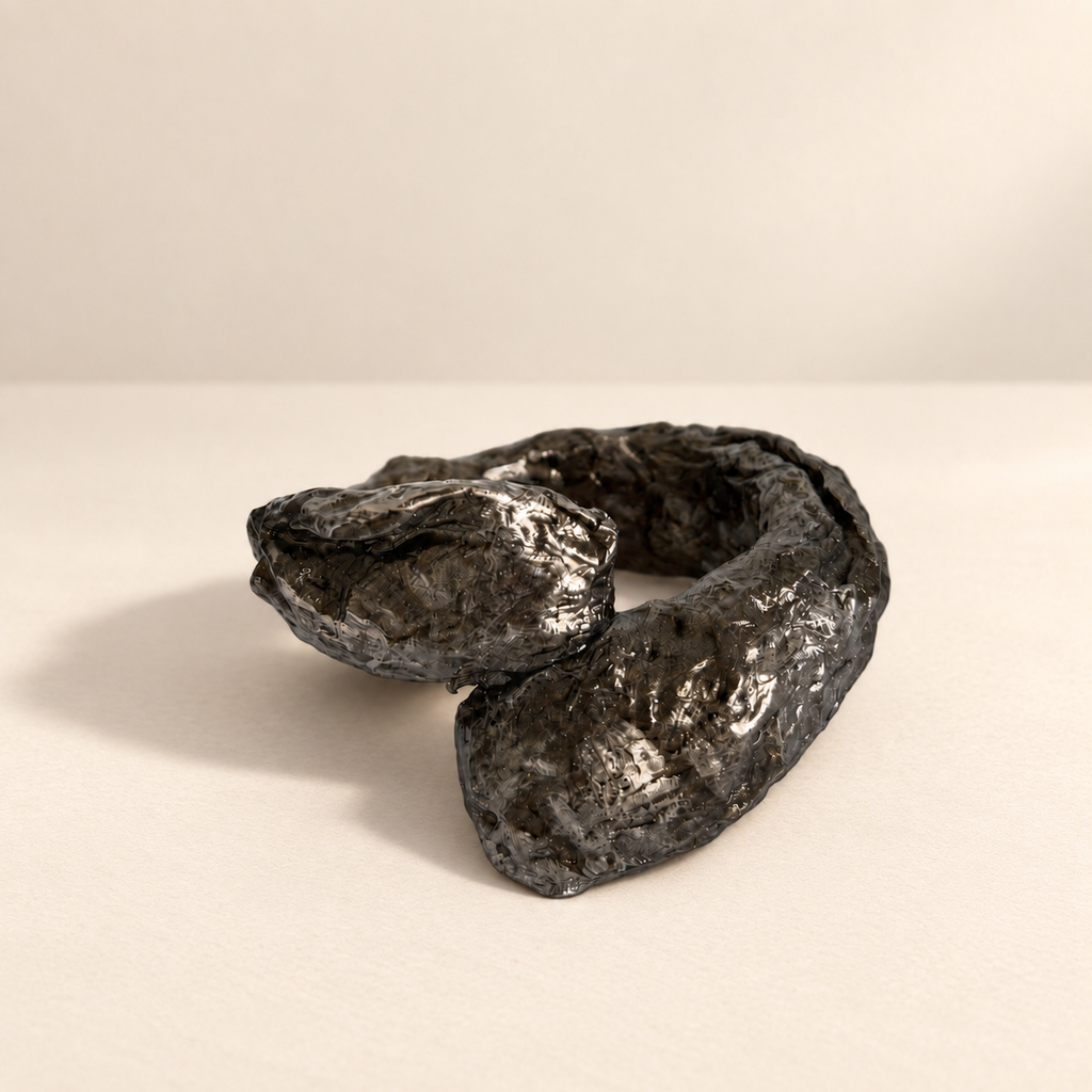 Obsidian Fold — Sculptural Paper Cuff Bracelet resting on a warm ivory studio surface with a natural grounding shadow — Niksa Design