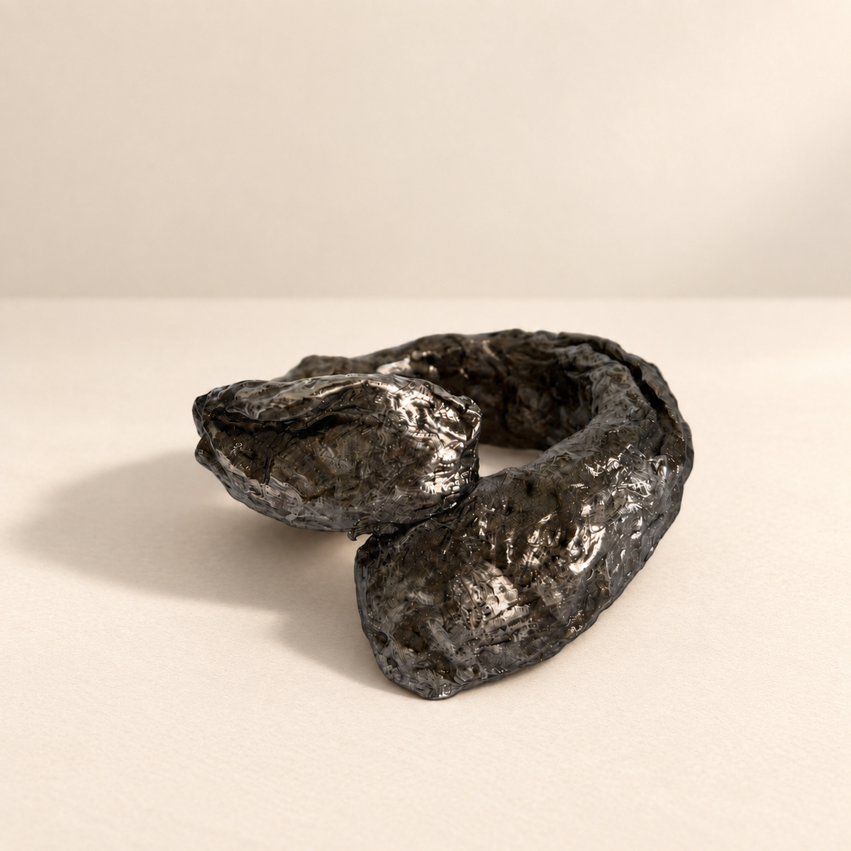 Obsidian Fold — Sculptural Paper Cuff Bracelet resting on a warm ivory studio surface with a natural grounding shadow — Niksa Design