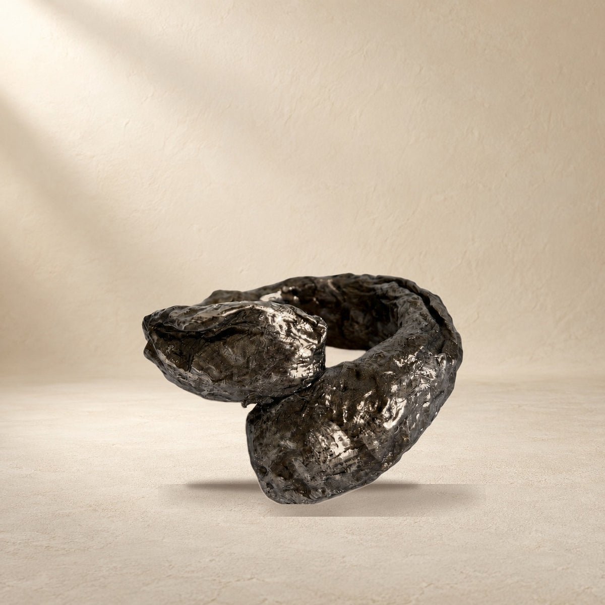 Obsidian Fold bracelet resting on a warm cream surface
