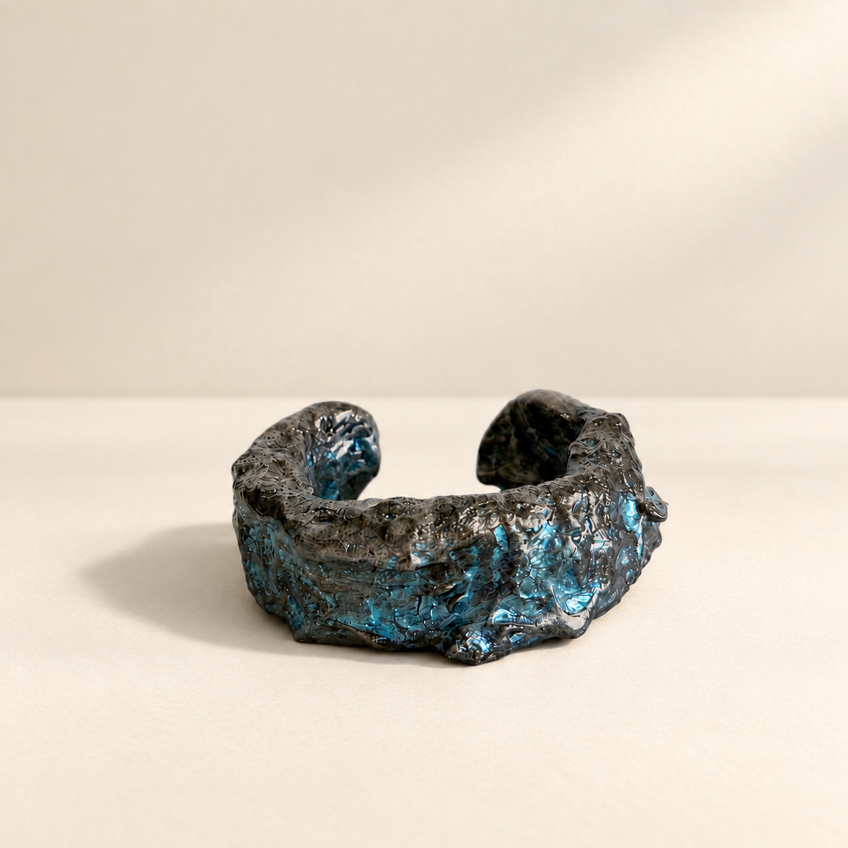 Tidal Fault — Sculptural Paper Cuff Bracelet resting on a warm ivory studio surface with a natural grounding shadow — Niksa Design