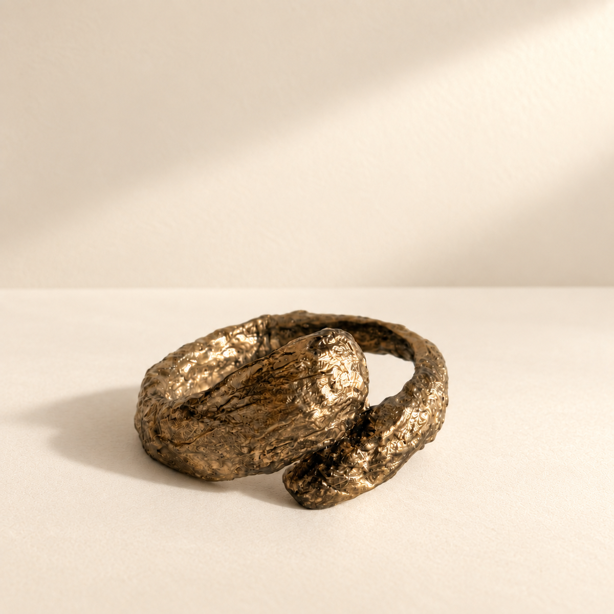 Gilded Confluence — Sculptural Handmade Paper Cuff Bracelet resting on a warm ivory studio surface with a natural grounding shadow — Niksa Design