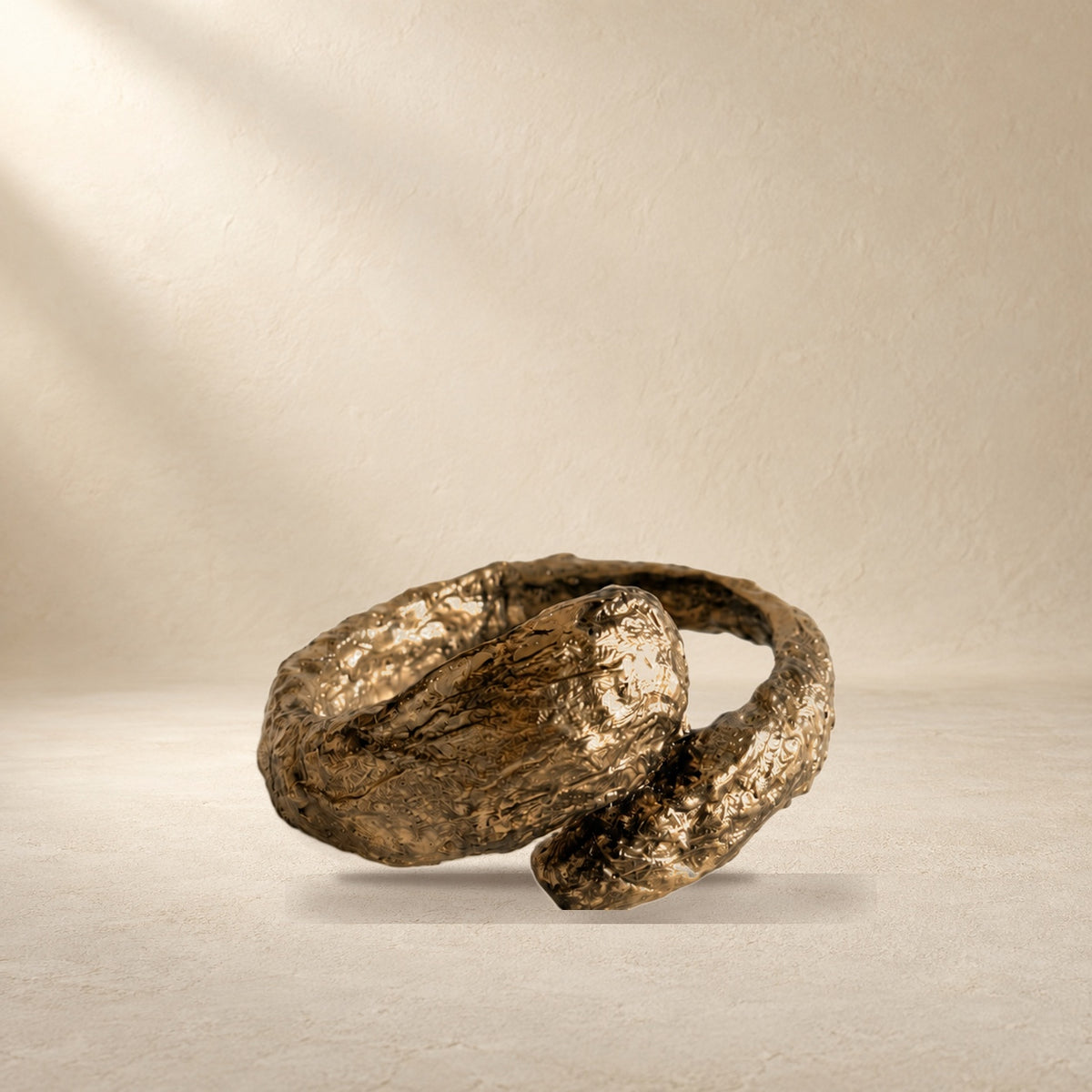 Gilded Confluence bracelet resting on a warm cream surface