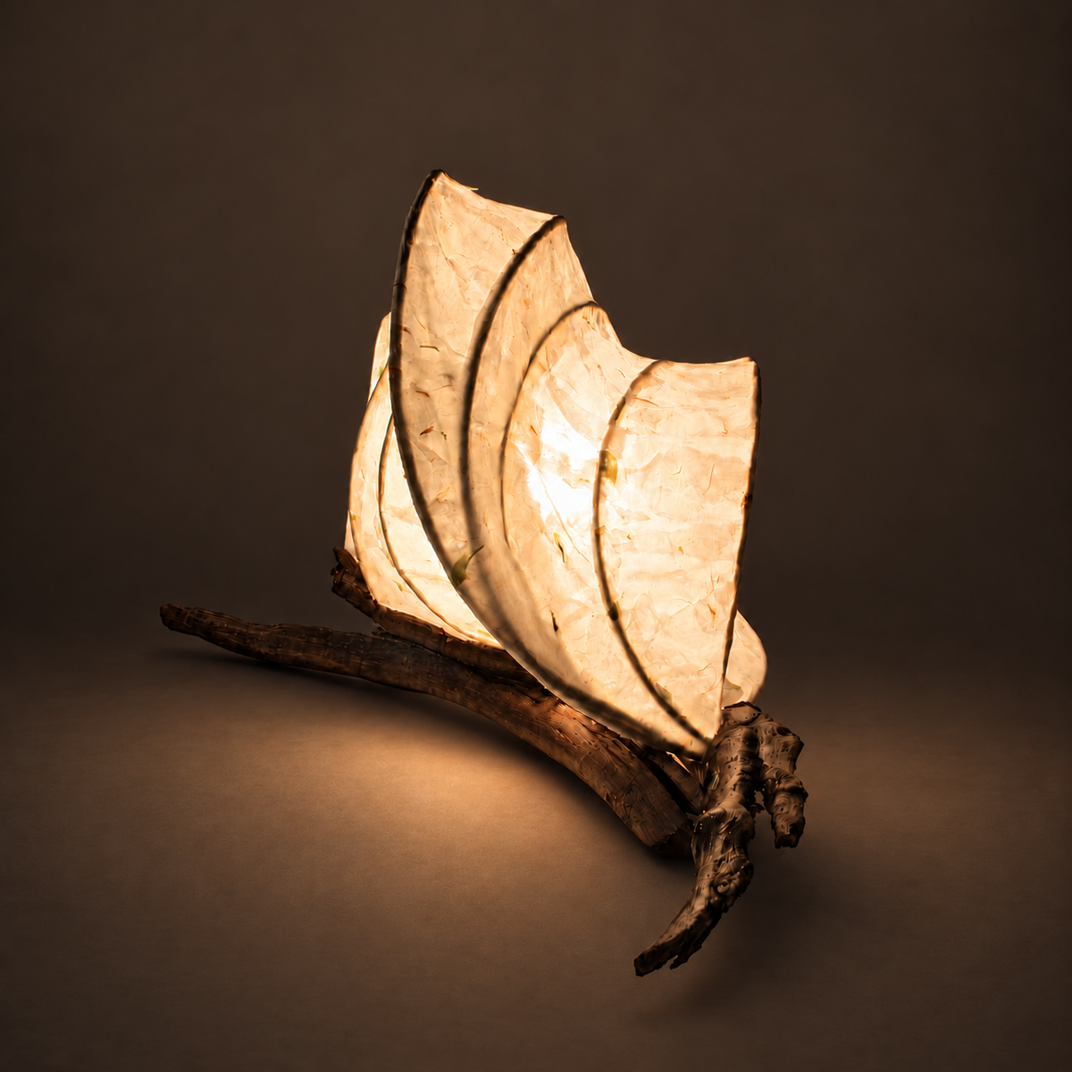 Leafrest sculptural lamp illuminated against warm charcoal