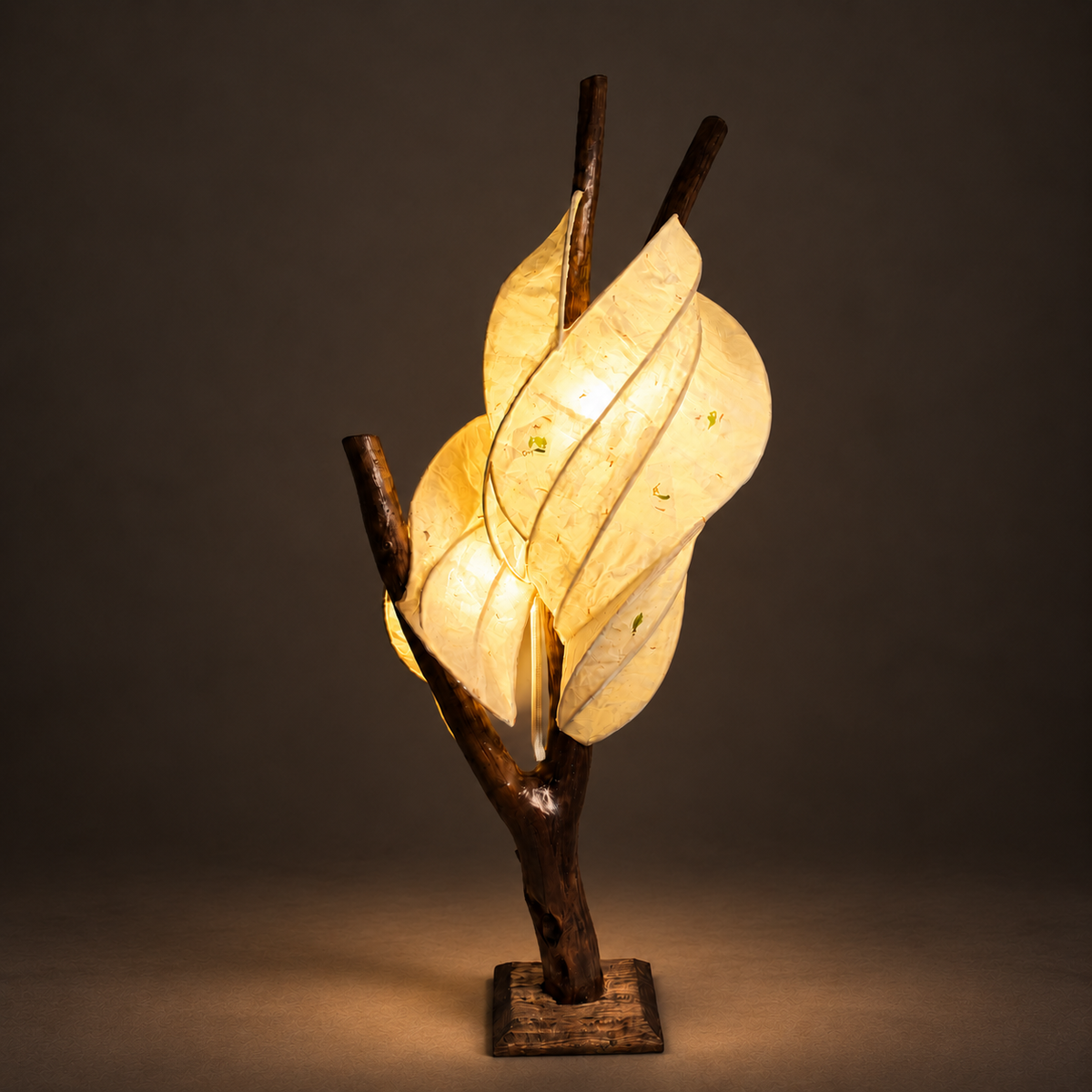 Moonleaf sculptural lamp illuminated against warm charcoal