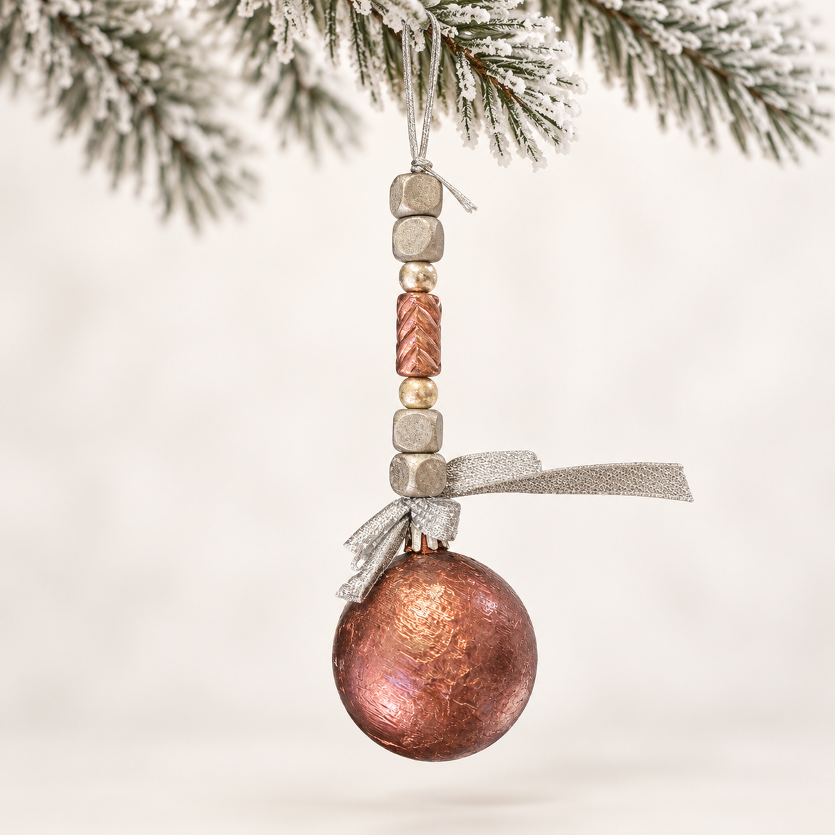 Copper-toned ball with silver-toned cube beads, a copper centre bead and a silver ribbon.