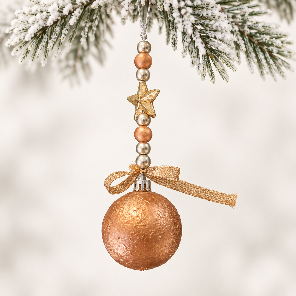 Copper-toned ball with a gold-toned star, mixed metallic beads and a gold-toned ribbon.