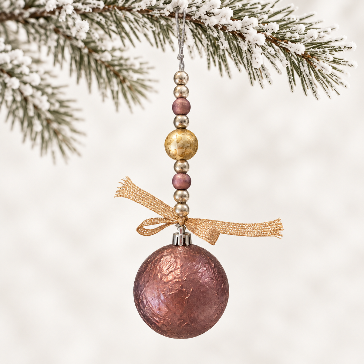 Rose-toned ball with metallic and marbled beads, finished with a gold-toned ribbon.