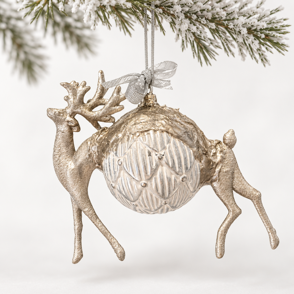Silver-toned deer form surrounding a patterned ivory and silver-toned sphere.