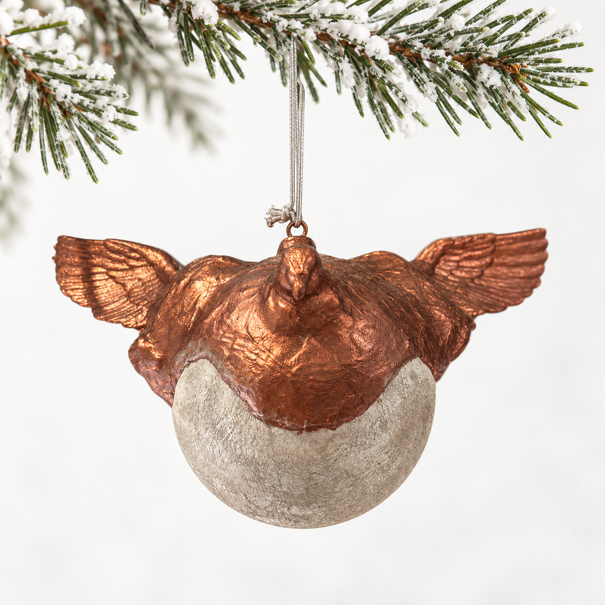 Copper-toned bird and outstretched wings above a textured silver-toned sphere.