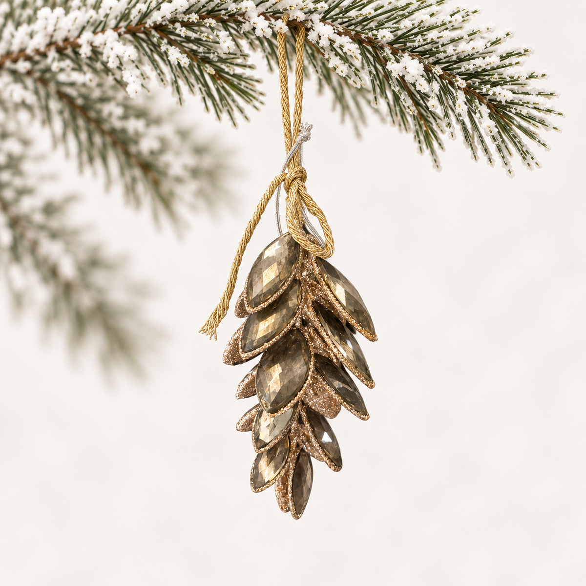Layered pinecone form with faceted bronze-toned accents and a gold-toned hanging cord.