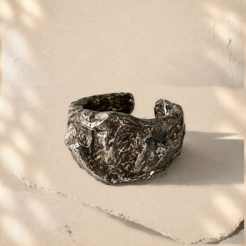 Compressed Shield — Sculptural Paper Cuff Bracelet on warm cream background