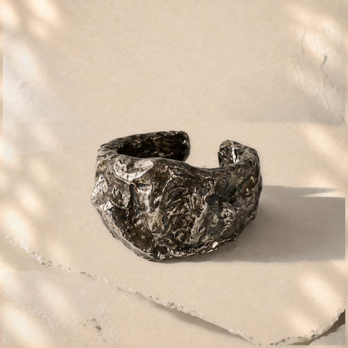 Compressed Shield — Sculptural Paper Cuff Bracelet on warm cream background