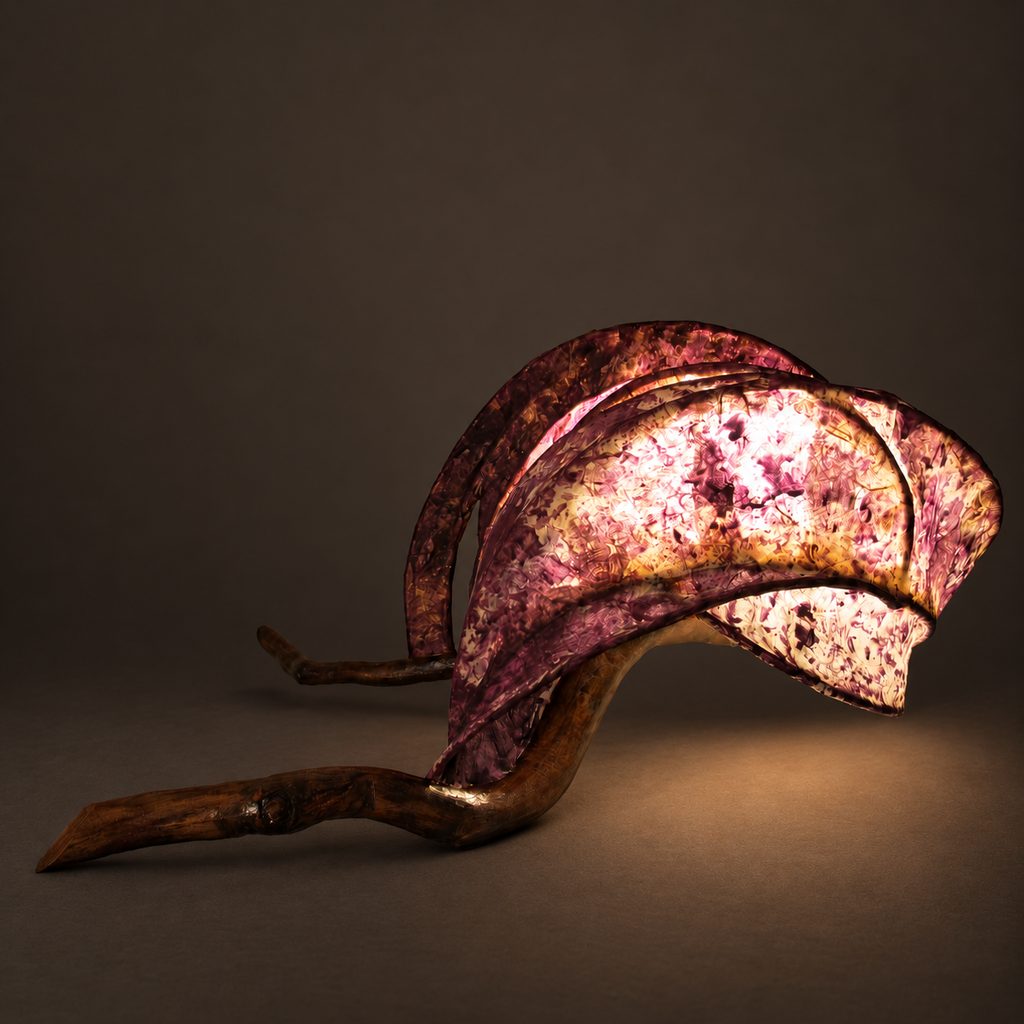 Rose Ember sculptural lamp illuminated against warm charcoal